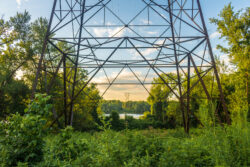 Power lines cross through a park and over the Connecticut River and attach to a tower on the other side.