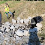 Water quality basin with rock channel at inlet to slow water and sediment transport