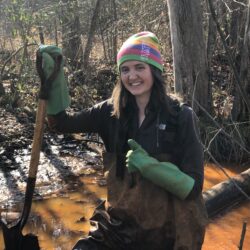 EnviroScience Restoration EIT Elizabeth Myers in acid mine drainage remediation fieldwork, wearing waders and gloves in an impacted Appalachian stream.