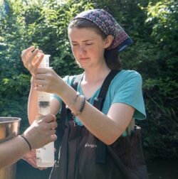 EnviroScience Restoration EIT Liz Myers conducting field water sampling in a forested stream environment for acid mine drainage research.