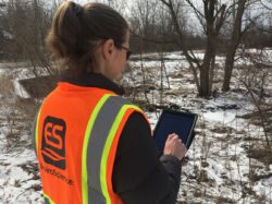 EnviroScience staff conducting environmental field inspection using a tablet, representing NEPA site review practices.
