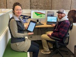 EnviroScience GIS specialists reviewing LiDAR-based elevation data and geospatial maps in an office setting for environmental analysis and reporting.