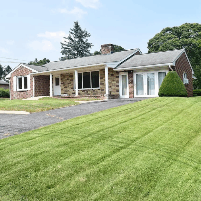 Front view of EnviroScience’s new State College, Pennsylvania office — a one-story brick and stone building with a covered porch, large front windows, and a well-manicured lawn.