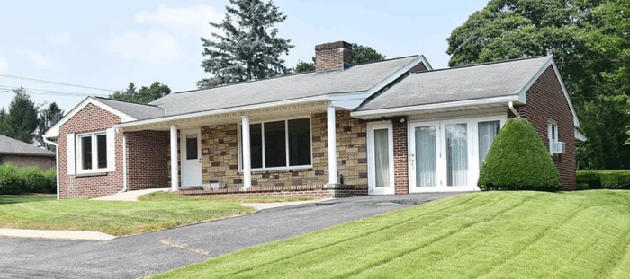 Front view of EnviroScience’s new State College, Pennsylvania office — a one-story brick and stone building with a covered porch, large front windows, and a well-manicured lawn.