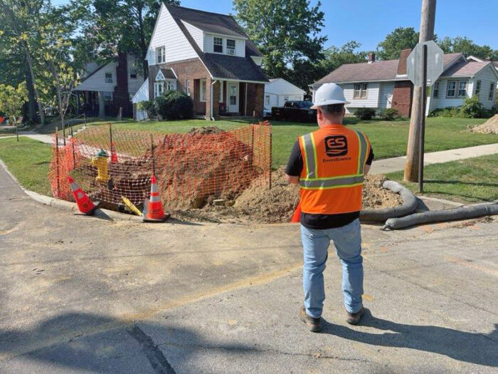 An EnviroScience inspector wearing a hard hat and safety vest observes a residential construction site, assessing stormwater controls and erosion prevention measures.