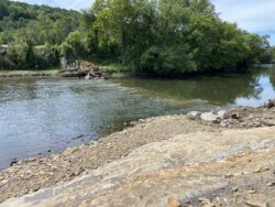 Excavator removing remaining dam structures from the Mahoning River at Lowellville, Ohio, as part of a river restoration and dam removal project.