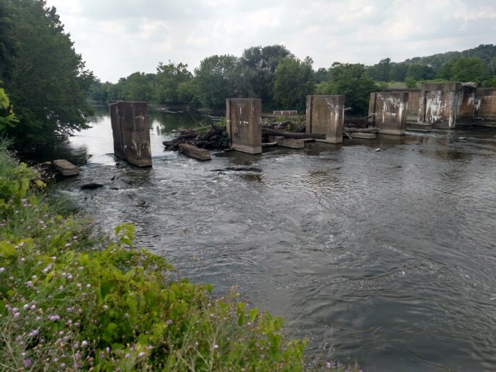 Concrete dam piers remain in the Mahoning River at Struthers, Ohio, as water flows freely through the former dam footprint following partial removal.